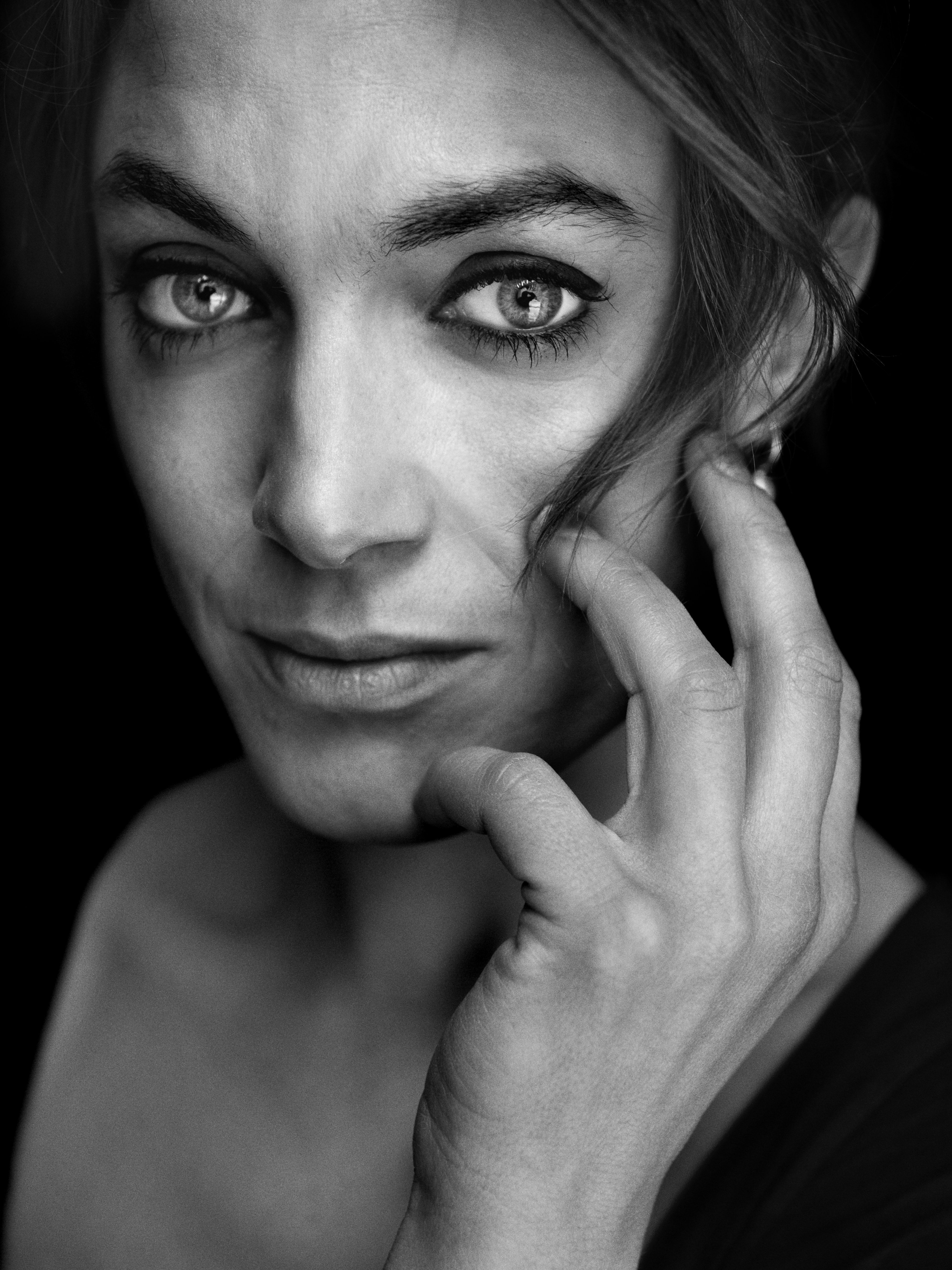 Porträttfoto i svartvitt av kvinna som ser med intensiv blick in i kameran.