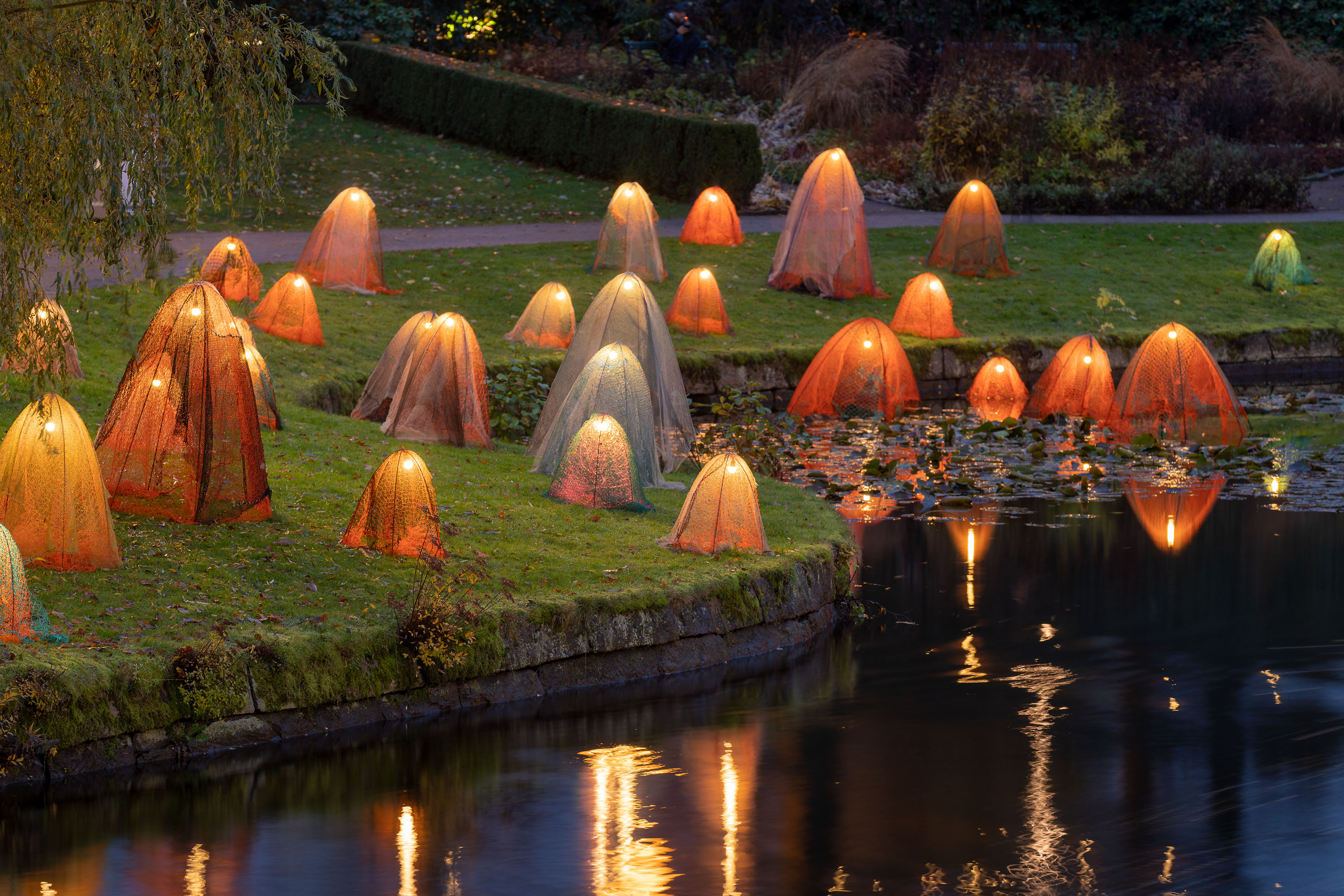 Kvällsmörker i park med orange lysande små spökliknande varelser