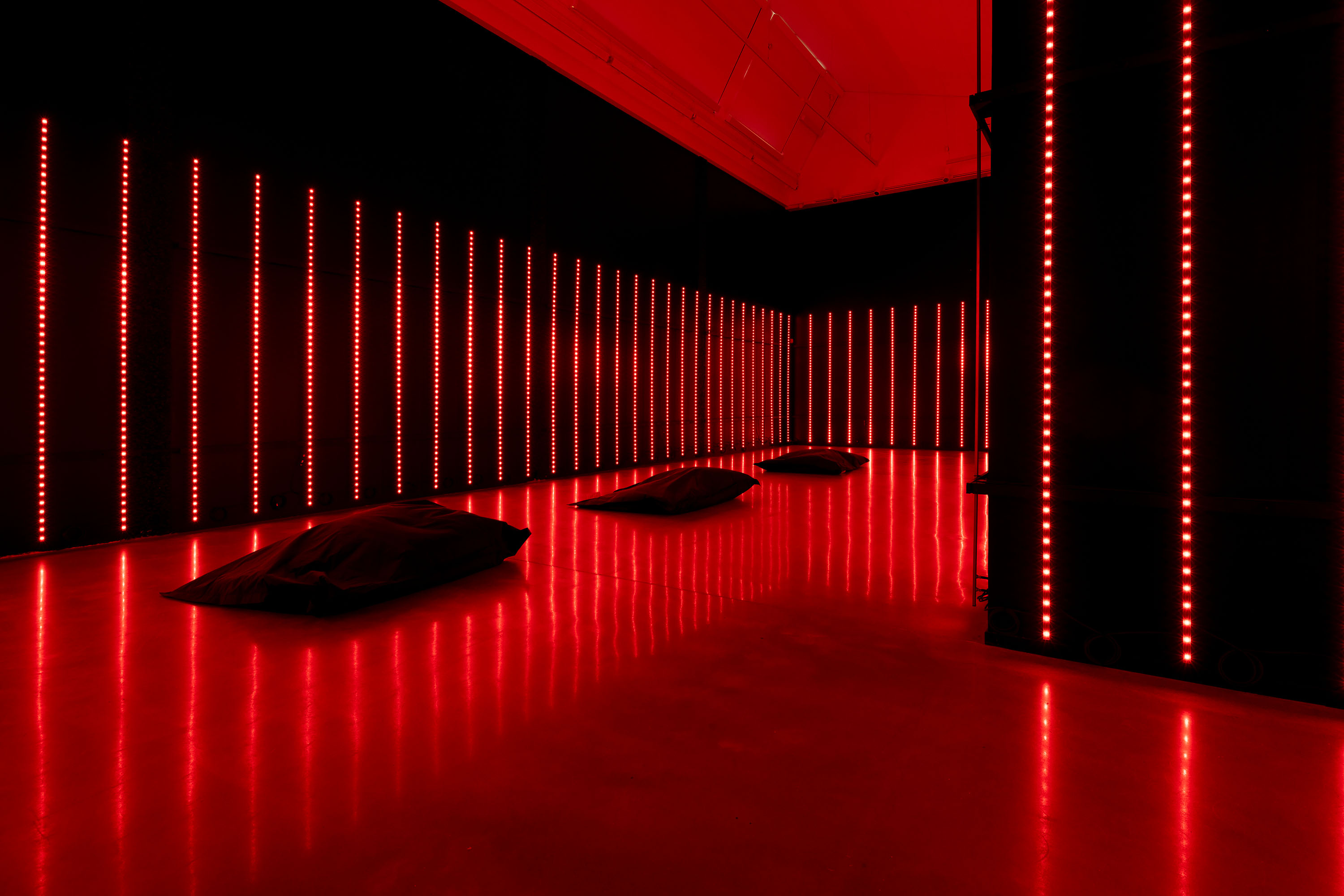 stort svart rum med högt itak, längs väggarna finns rött lysande ljusrader