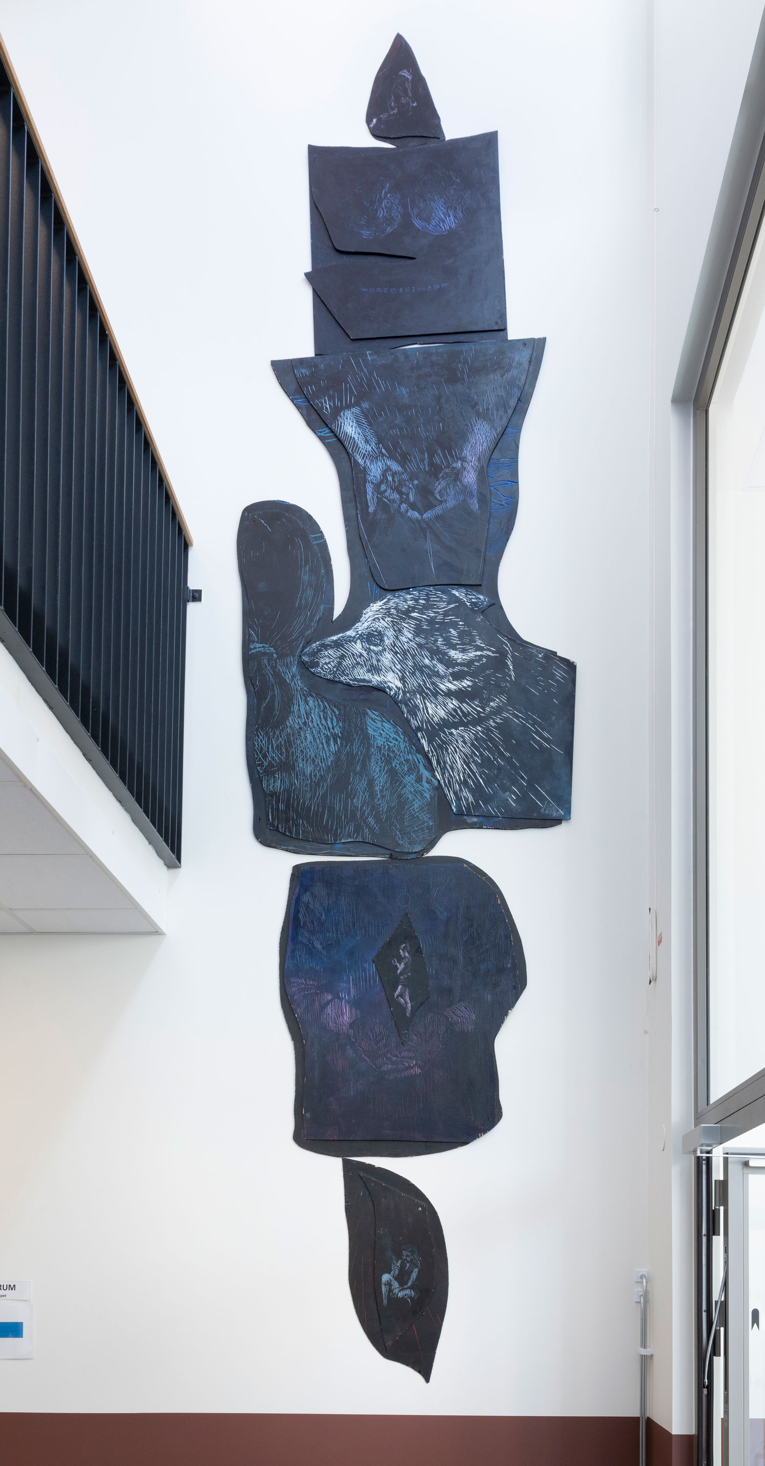 konstverk av blåmålade träskivor i avlång formation på vägg i skola