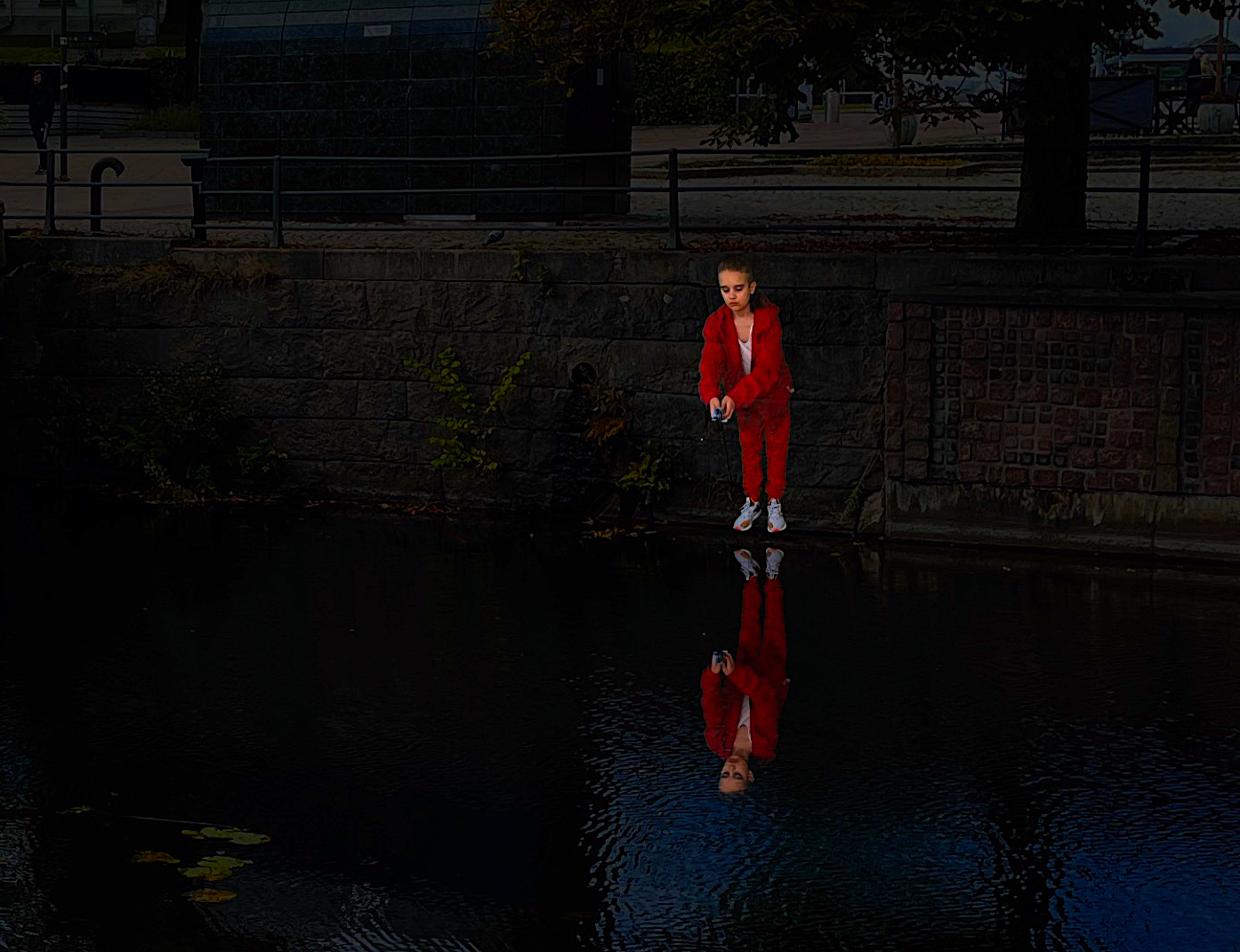 Kvällsmörker i stadsmiljö med en projicerad flicka i röda kläder som håller ett fiskspö ovanför ett vattendrag