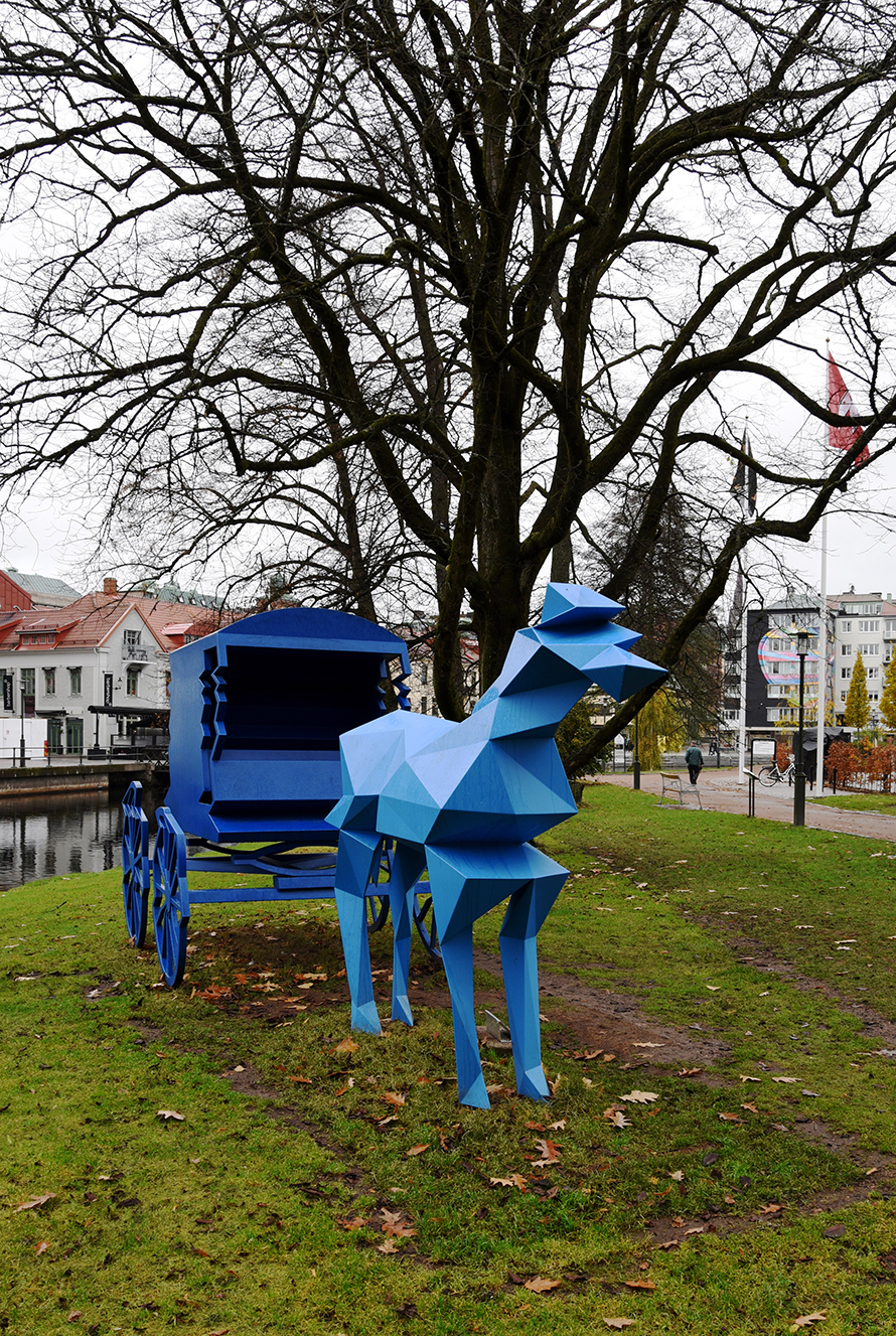 Blå skulptur av häst och vagn.