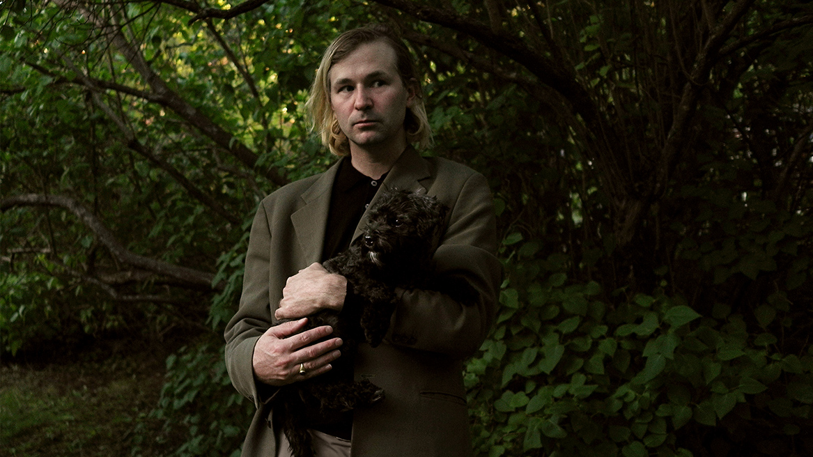 foto i skogsparti av Isak Sundström hållandes en hund