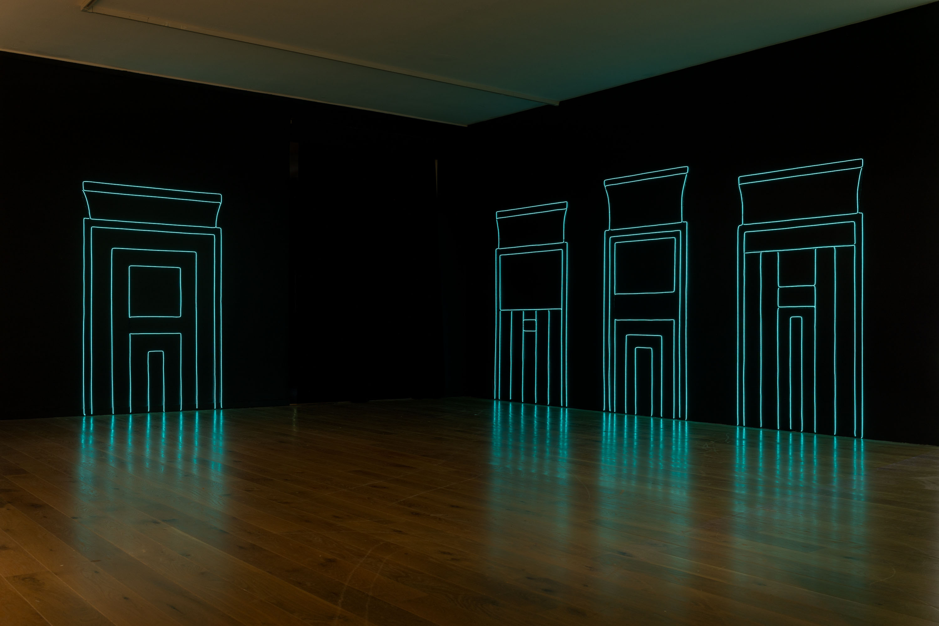 mörkt rum med svarta väggar där tre portaler formade av ljustråd är uppspända