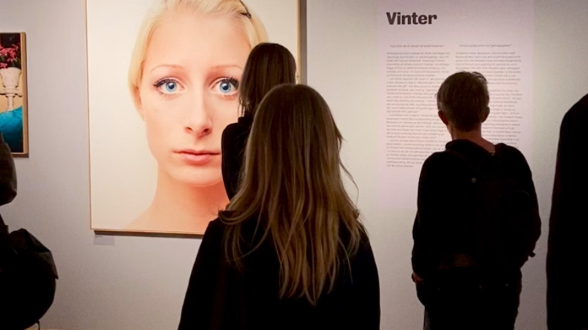 fyra personer tittar på fotografier som hänger på museet