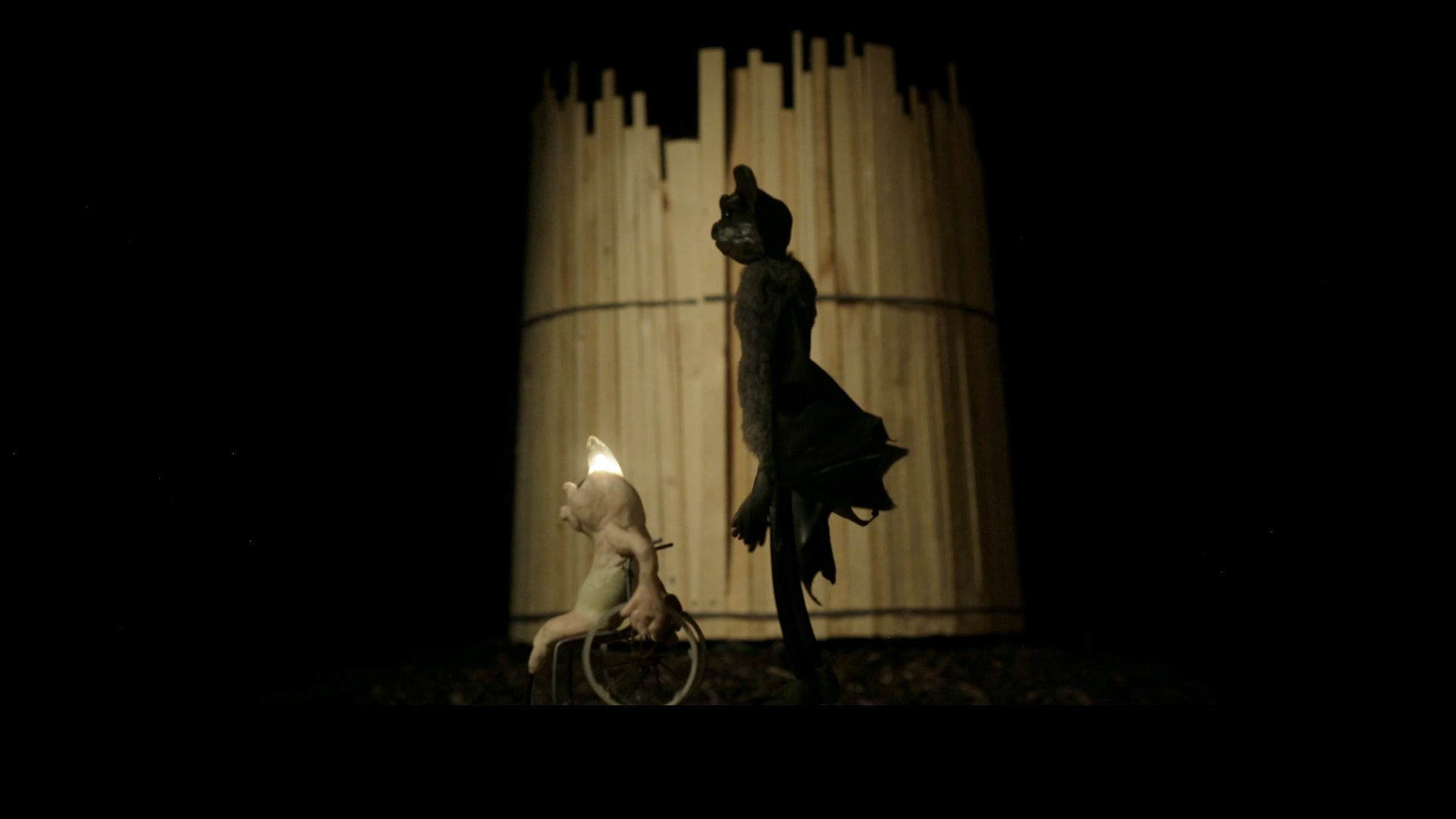 Stillbild från film, rullstolsburen lysmask och skugga av en fladdermus.