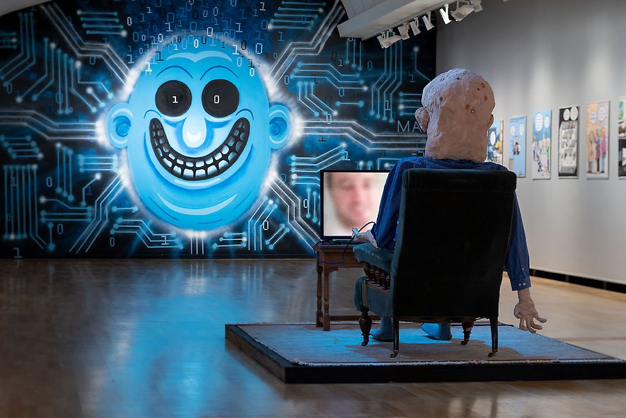 Rum med en skulptur av en person i till synes psykostillstånd som tittar på en TV-skärm